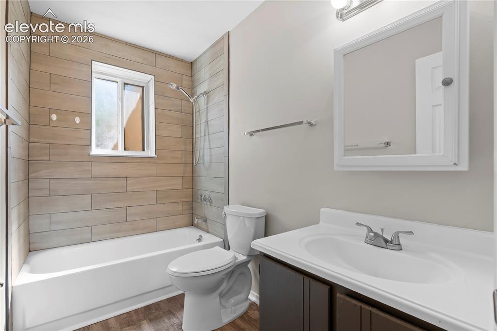 Image 16 of 32: Bathroom featuring wood-look tile shower surround, white bathtub, chrome sh