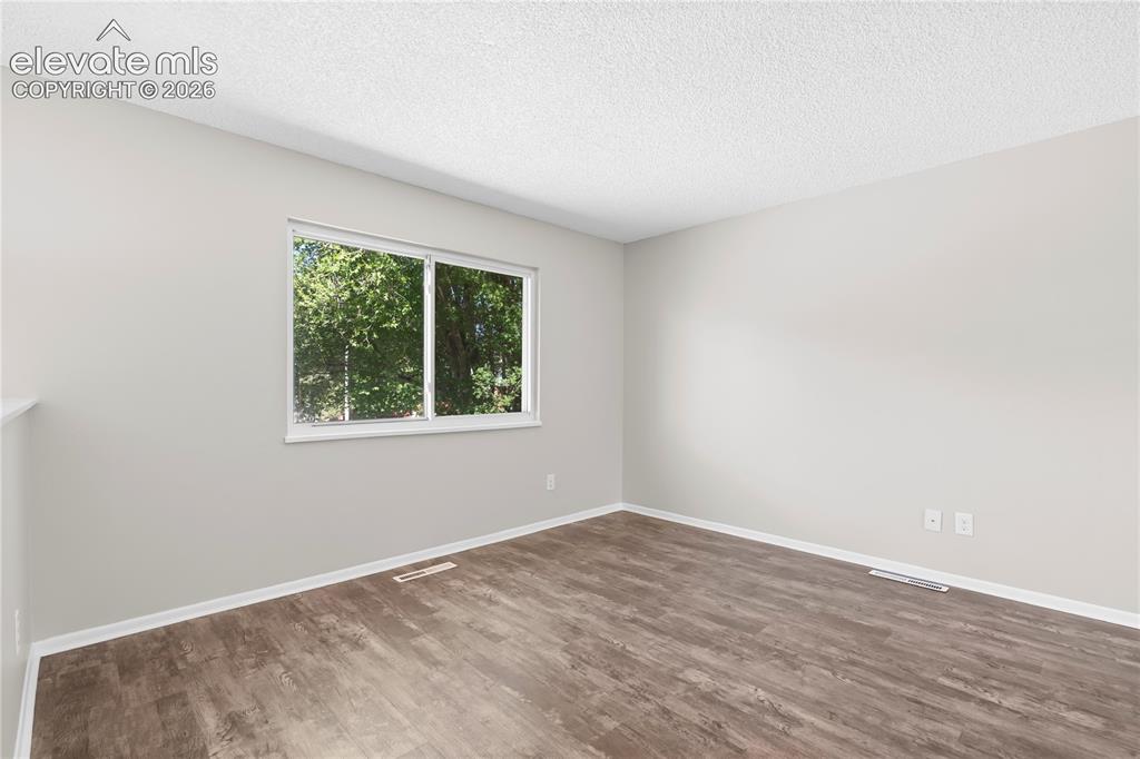Image 17 of 32: Room with wood-finish flooring, white baseboards, and light gray walls