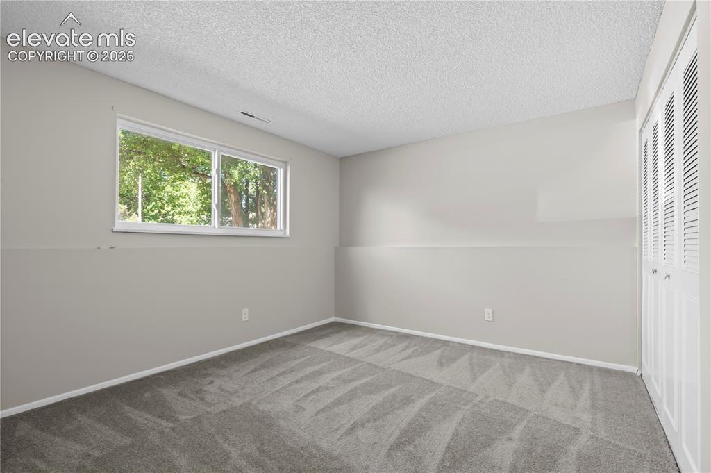 Image 18 of 32: Spacious room featuring neutral paint, gray patterned carpeting, a large do