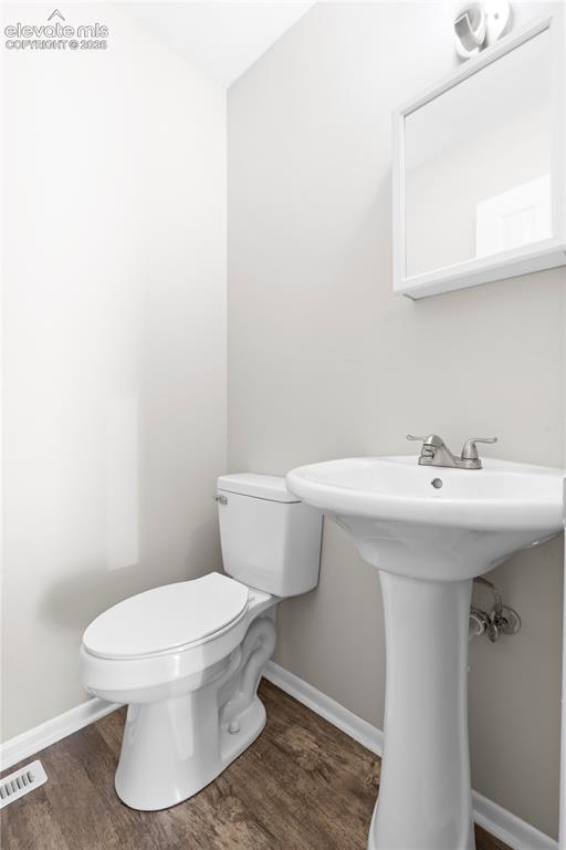 Image 20 of 32: Compact bathroom featuring a white pedestal sink, toilet, and wood-finish f