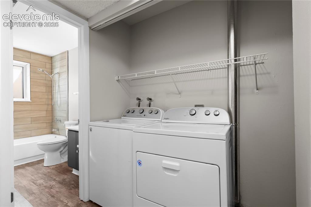 Image 21 of 32: Dedicated laundry area featuring white appliances and upper wire shelving