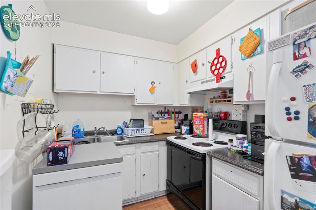Image 24 of 32: Compact kitchen featuring white cabinetry and appliances