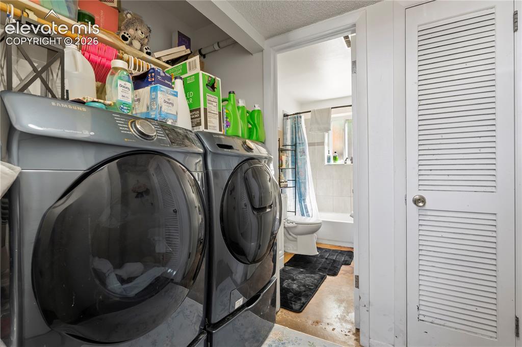 Image 27 of 32: Dedicated laundry area featuring a front-loading washer and dryer, open she