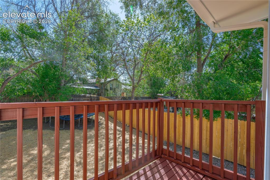 Image 29 of 32: Exterior deck with rich brown wood railing and decking, offering a broad pe