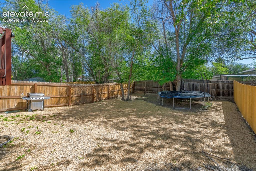 Image 30 of 32: Spacious backyard featuring wood fencing and mature trees