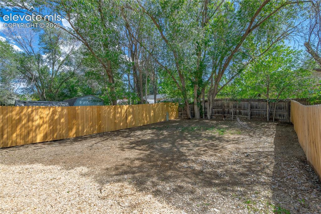 Image 6 of 32: Spacious rear yard with a new wood privacy fence, mature trees, and a combi