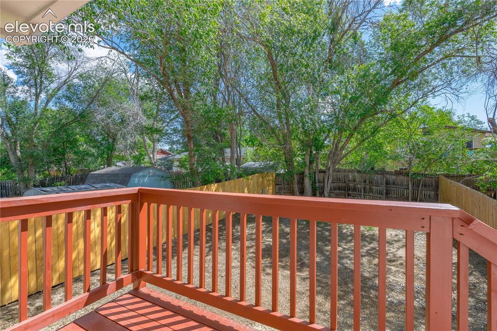 Image 7 of 32: Spacious backyard featuring a wooden privacy fence, mature trees, and a gro