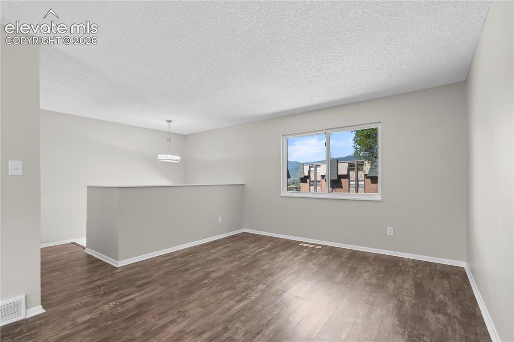 Image 9 of 32: Expansive room featuring wood-finish flooring, a contemporary ceiling light