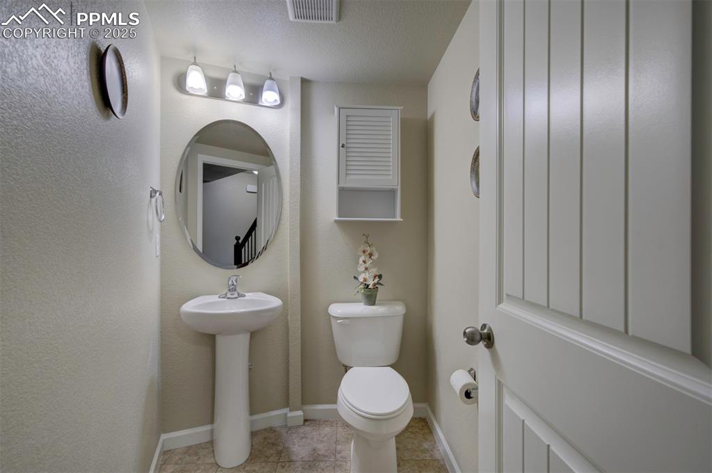 Image 12 of 34: Half bathroom on main level featuring tile patterned floors & single vanity
