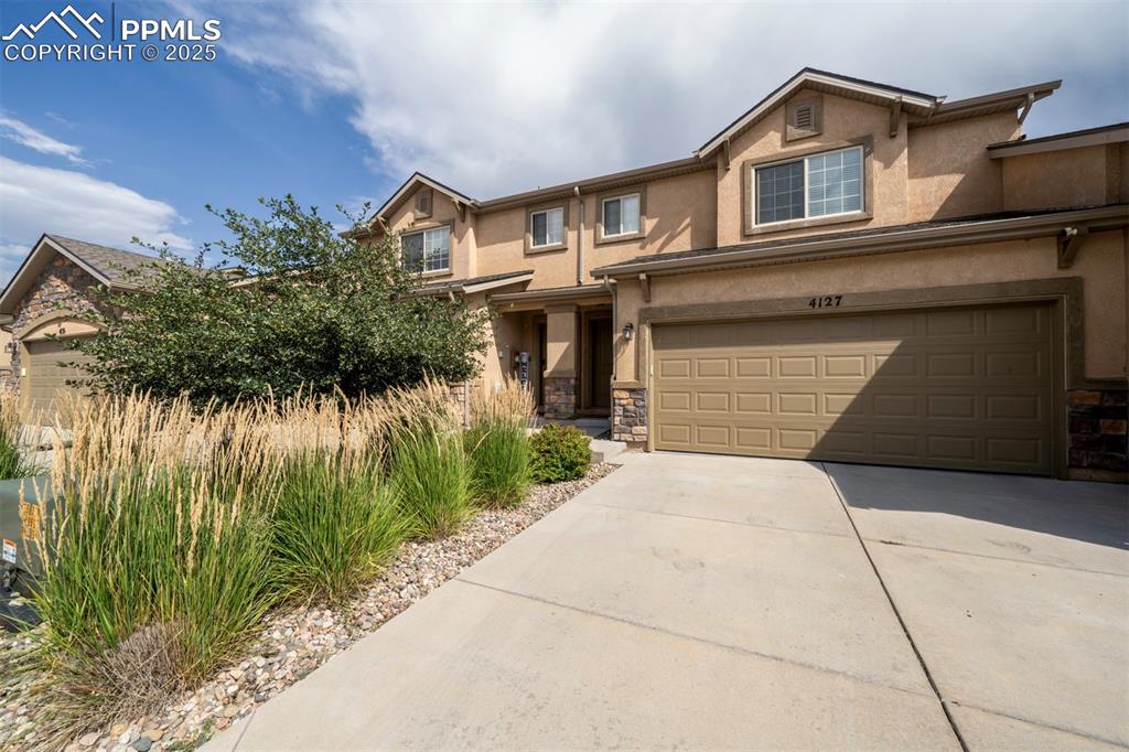 Image 2 of 34: Traditional home with stucco siding, concrete driveway, and stone siding