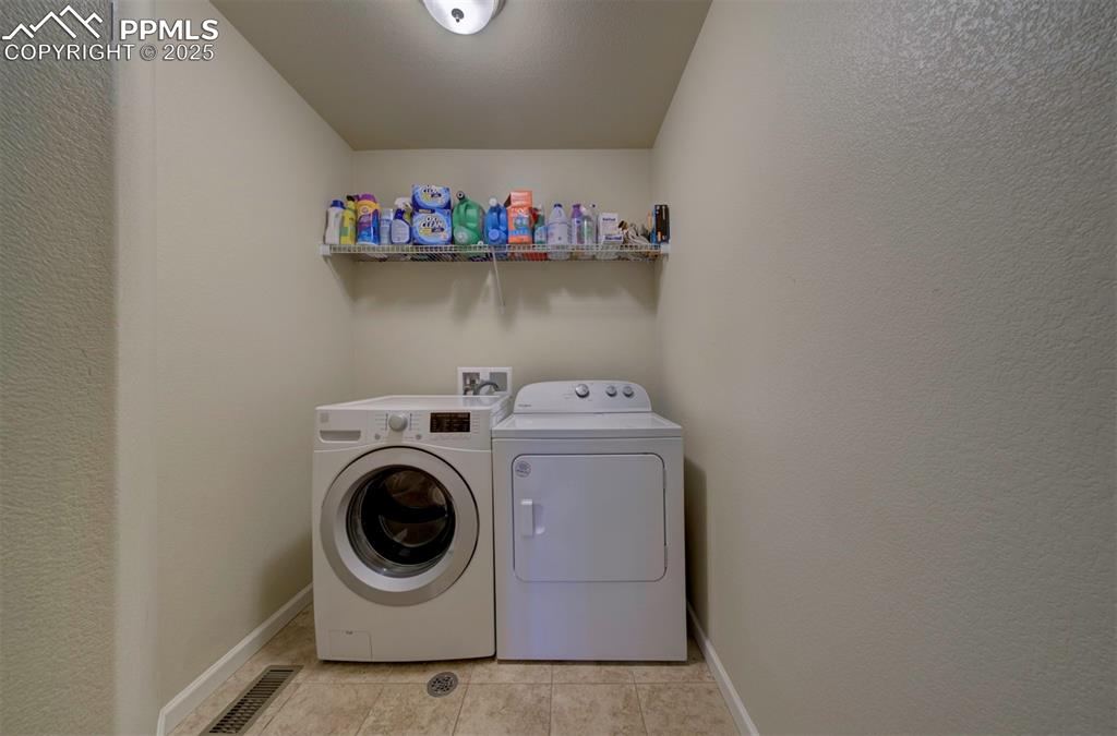 Image 21 of 34: Laundry area with washing machine and clothes dryer, light tile patterned f