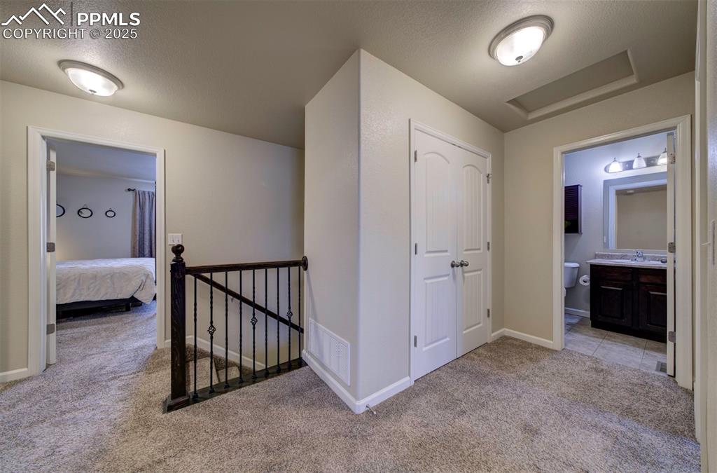 Image 23 of 34: Hallway featuring carpet, a textured ceiling, an upstairs landing, and atti