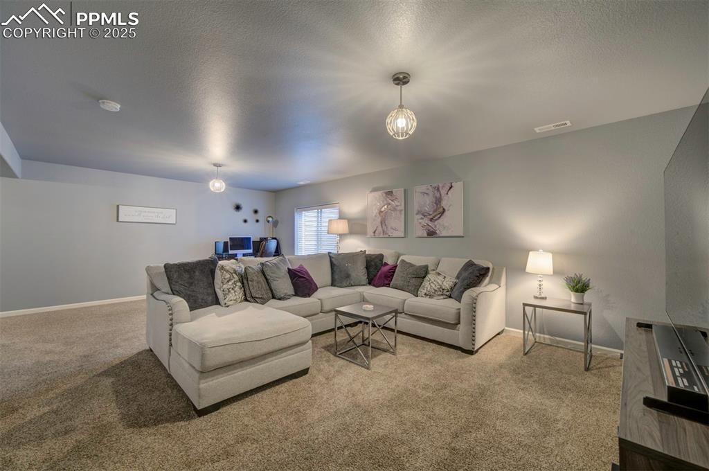 Image 24 of 34: Carpeted living room featuring a textured ceiling and baseboards