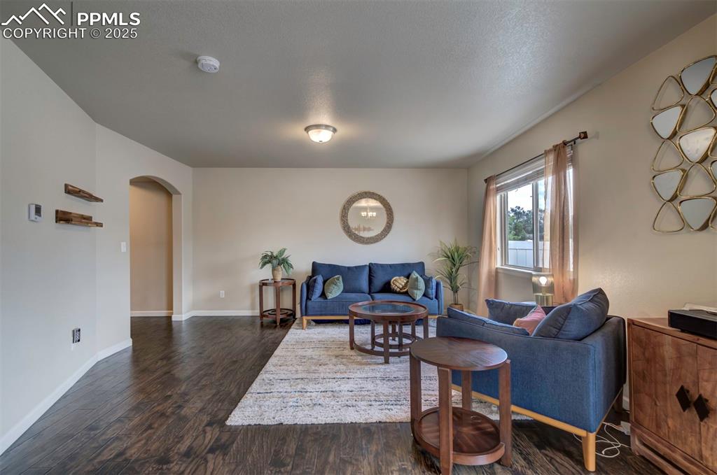 Image 5 of 34: Living area with arched walkways and wood flooring