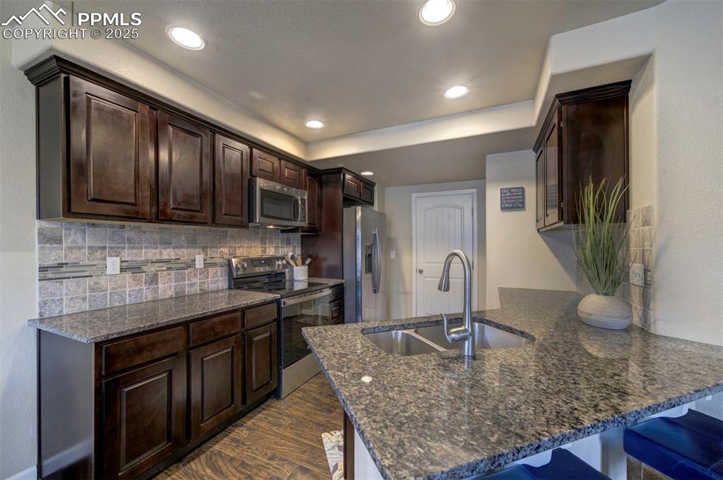 Image 9 of 34: Kitchen featuring appliances with stainless steel finishes, a peninsula, da