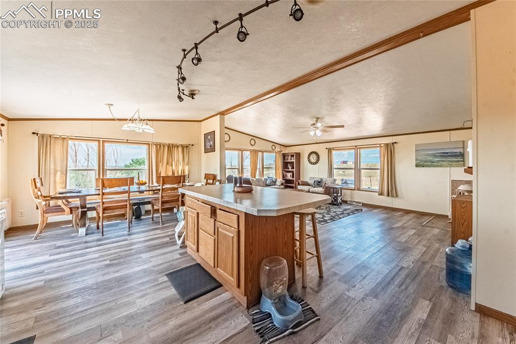 Image 10 of 48: Kitchen featuring lofted ceiling, a textured ceiling, a kitchen bar, wood f