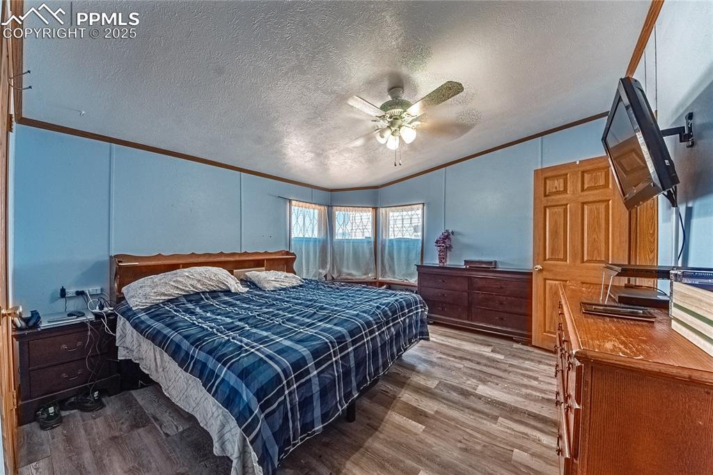 Image 17 of 48: Bedroom featuring ornamental molding, a decorative wall, wood finished floo