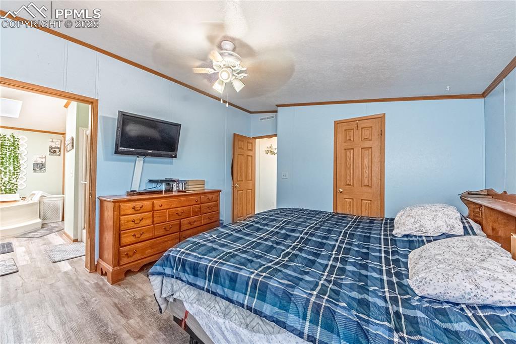 Image 19 of 48: Bedroom with light wood-style floors, ornamental molding, a ceiling fan, an