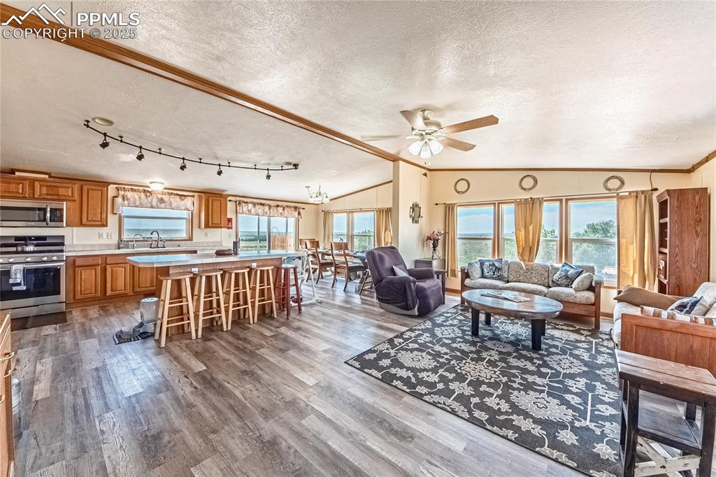 Image 2 of 48: Living room with a textured ceiling, lofted ceiling, a ceiling fan, wood fi