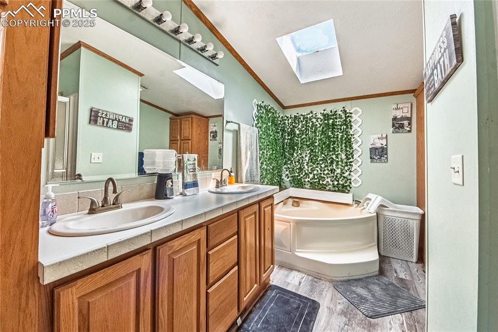 Image 21 of 48: Full bathroom featuring vaulted ceiling, a skylight, wood finished floors, 