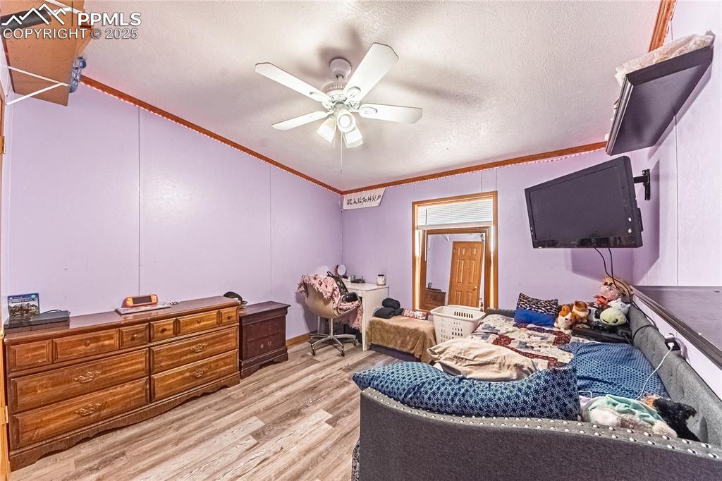 Image 24 of 48: Bedroom with ornamental molding, light wood-style flooring, a textured ceil