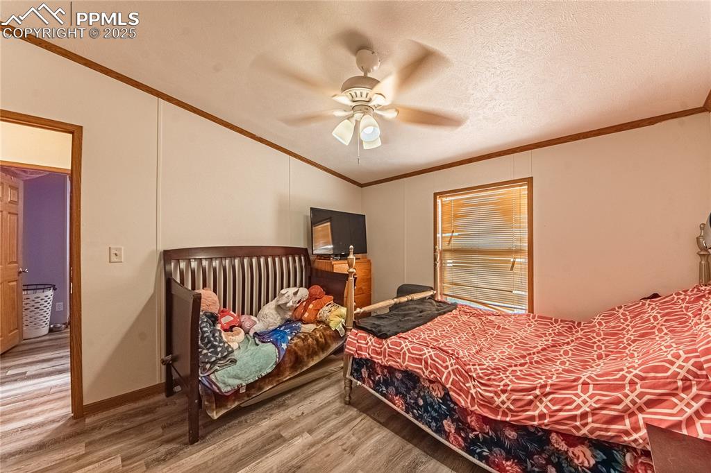 Image 27 of 48: Bedroom with wood finished floors, ornamental molding, ceiling fan, and vau