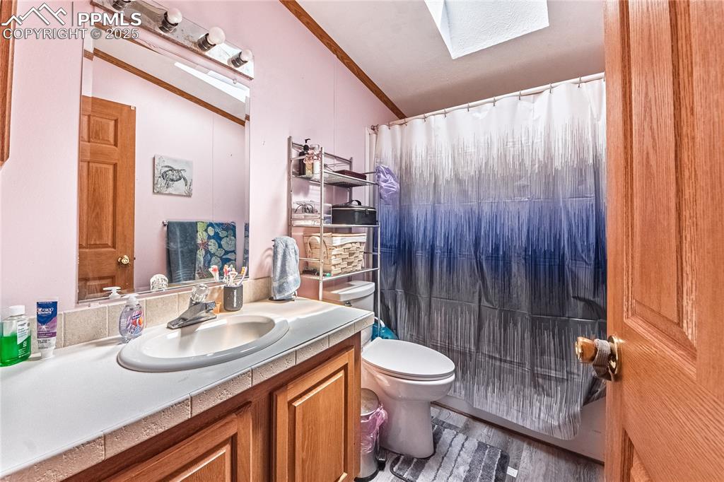 Image 28 of 48: Full bath with a skylight, vanity, wood finished floors, a shower with show