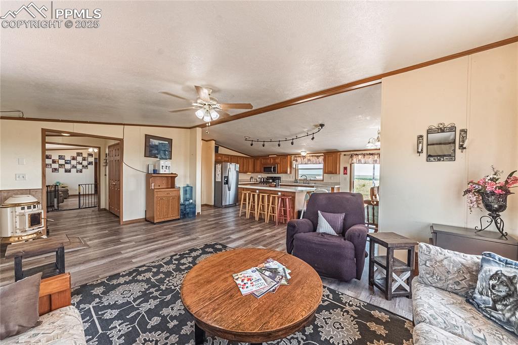Image 3 of 48: Living area with dark wood finished floors, ceiling fan, lofted ceiling, or