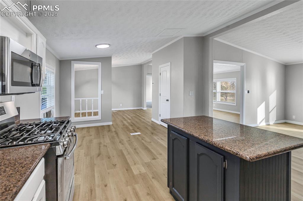 Image 14 of 34: Kitchen featuring lofted ceiling, light wood-type flooring, crown molding,