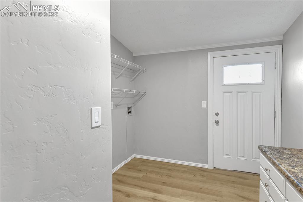 Image 20 of 34: Clothes washing area with crown molding, cabinets, washer hookup, and light