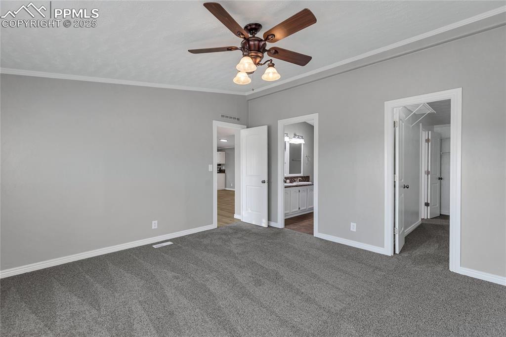 Image 22 of 34: Unfurnished bedroom featuring dark carpet, sink, ceiling fan, ornamental mo
