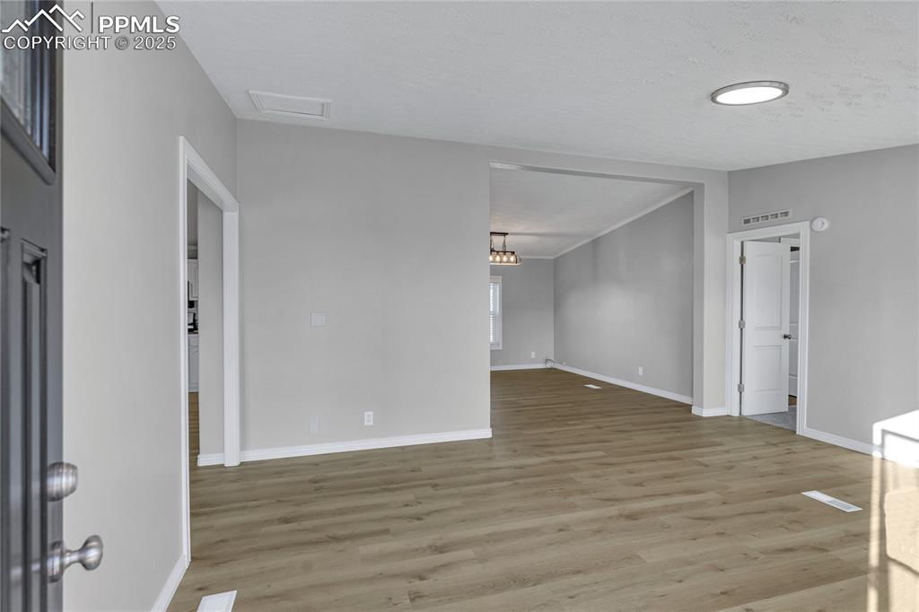 Image 6 of 34: Unfurnished room with light hardwood / wood-style floors and a textured cei