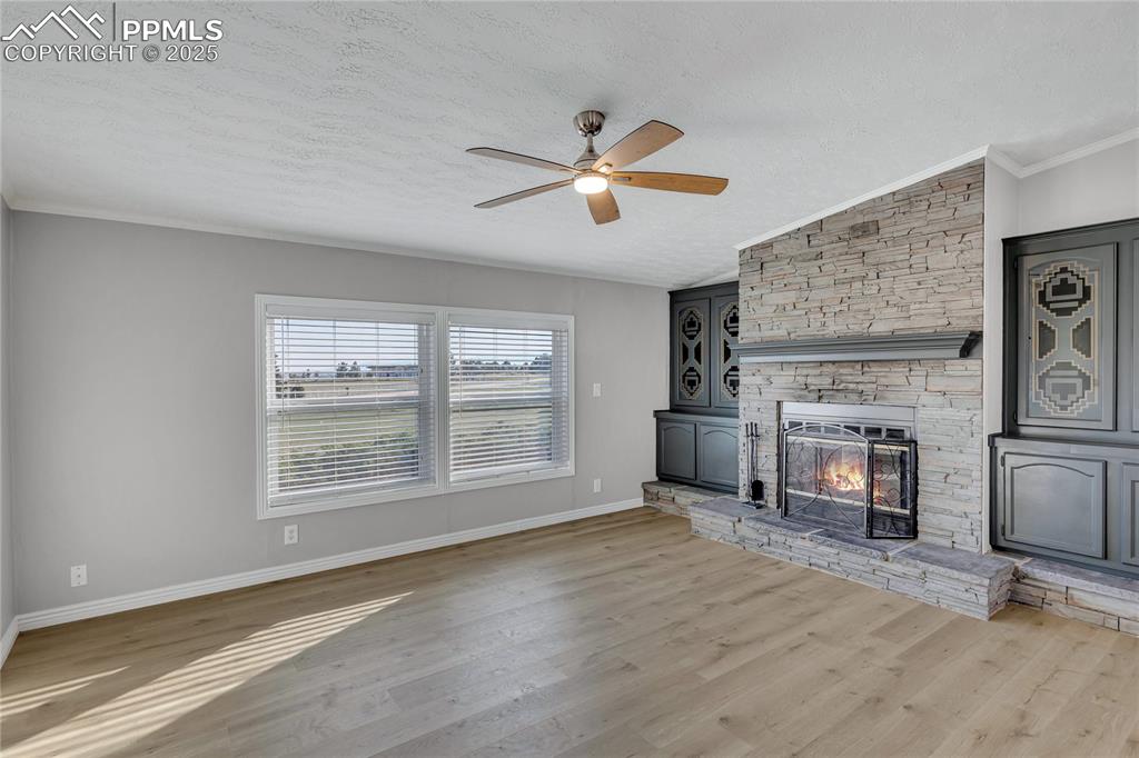 Image 8 of 34: Unfurnished living room featuring light wood-type flooring, a textured ceil