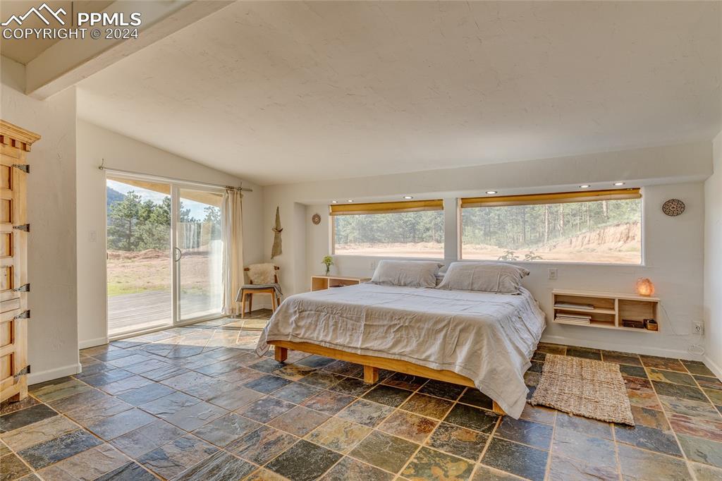 Image 12 of 47: Bedroom featuring tile flooring, access to exterior, and lofted ceiling wit