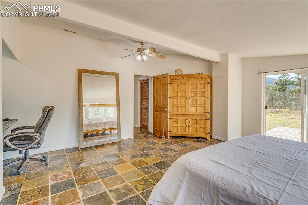Image 14 of 47: Tiled bedroom featuring access to outside, vaulted ceiling with beams, and