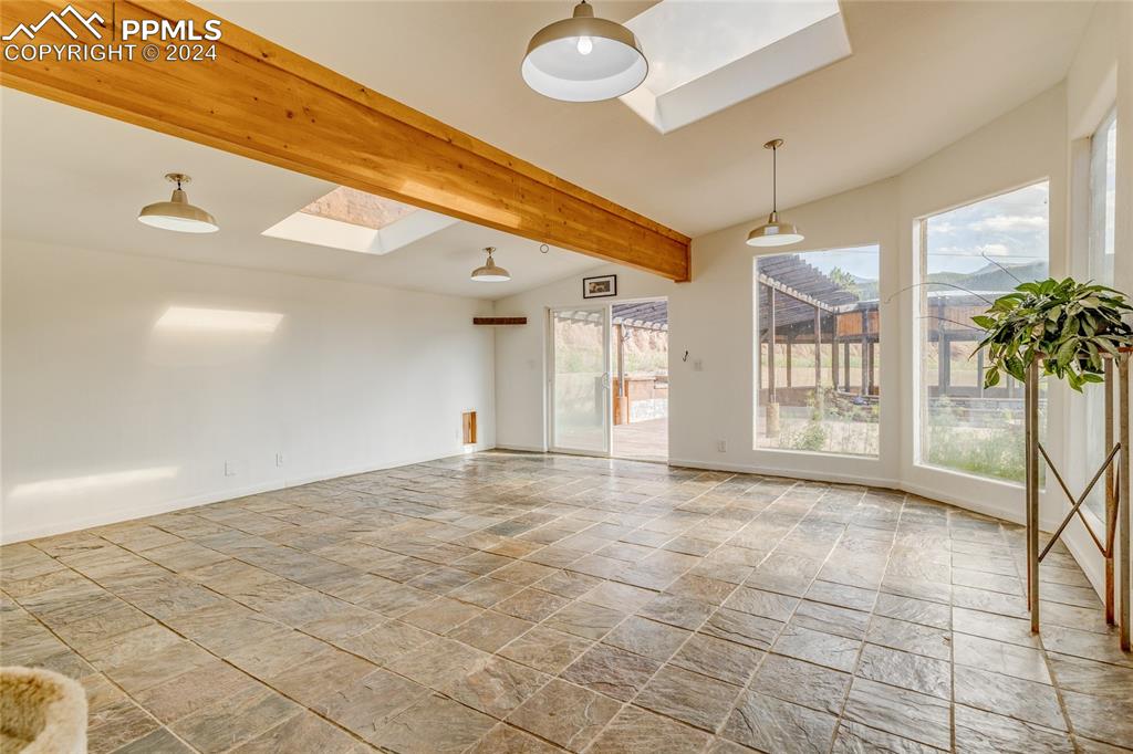 Image 16 of 47: Spare room featuring lofted ceiling with skylight and light tile flooring