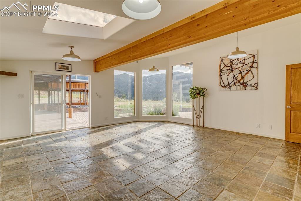 Image 17 of 47: Empty room with light tile floors, a skylight, and a mountain view
