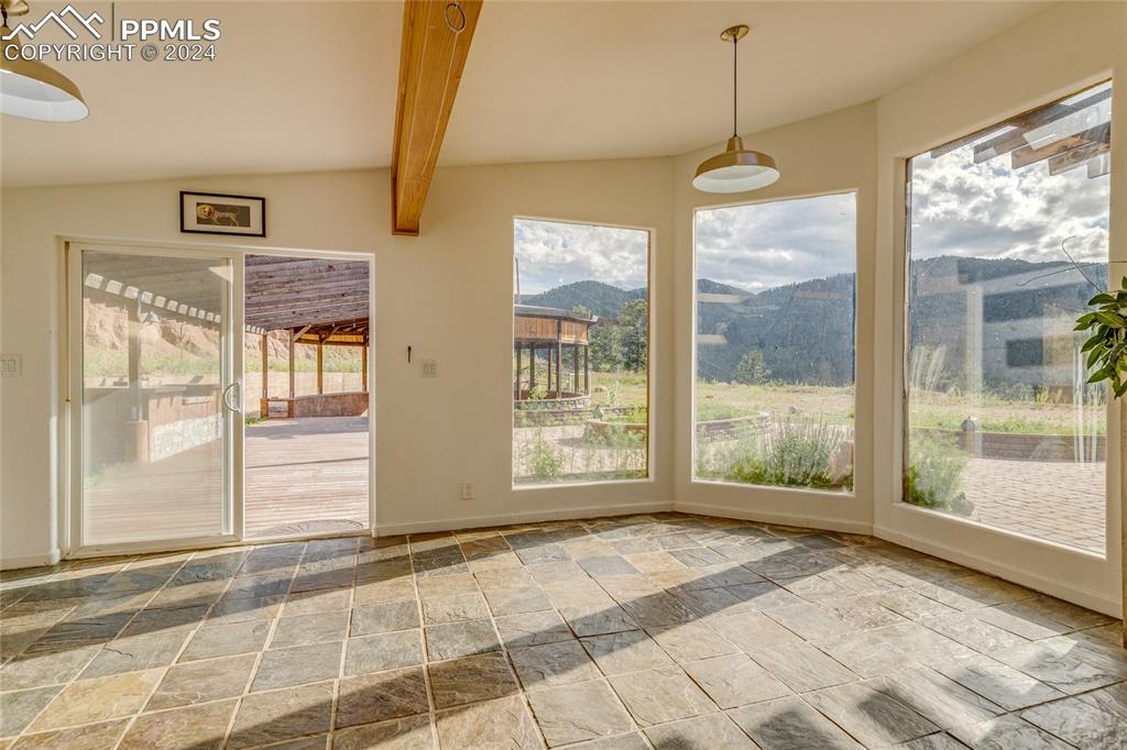 Image 18 of 47: Unfurnished sunroom featuring lofted ceiling with beams and a mountain view
