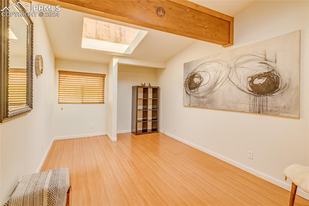 Image 26 of 47: Empty room featuring vaulted ceiling with skylight and light wood-type floo