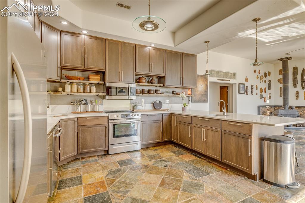 Image 4 of 47: Kitchen with decorative light fixtures, kitchen peninsula, appliances with