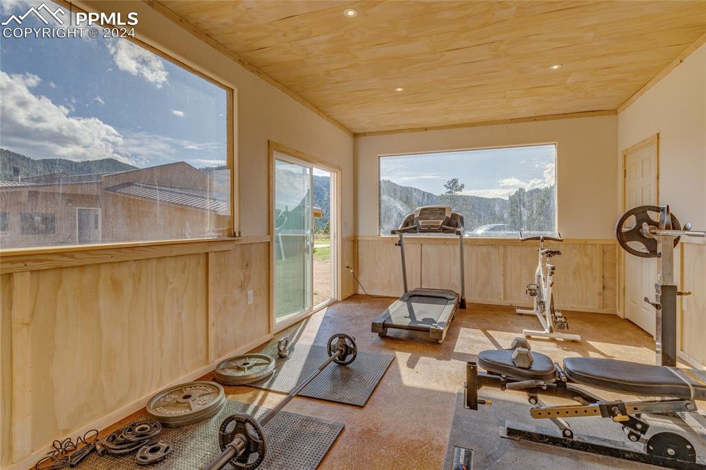 Image 45 of 47: Workout room with plenty of natural light, wood ceiling, and a mountain vie