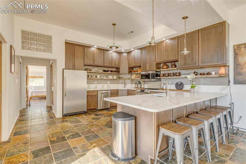 Image 5 of 47: Kitchen with pendant lighting, stainless steel appliances, kitchen peninsul
