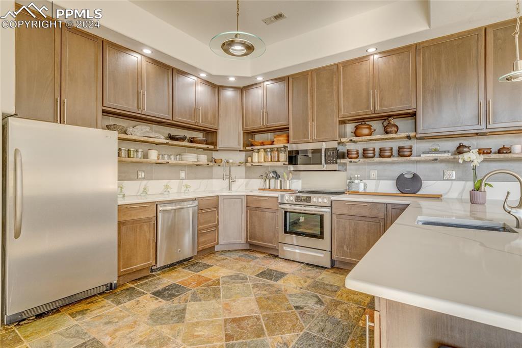 Image 6 of 47: Kitchen with pendant lighting, appliances with stainless steel finishes, ti