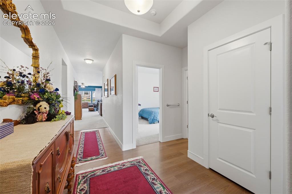Image 14 of 25: Hallway featuring wood-finish flooring, white paneled doors with chrome har
