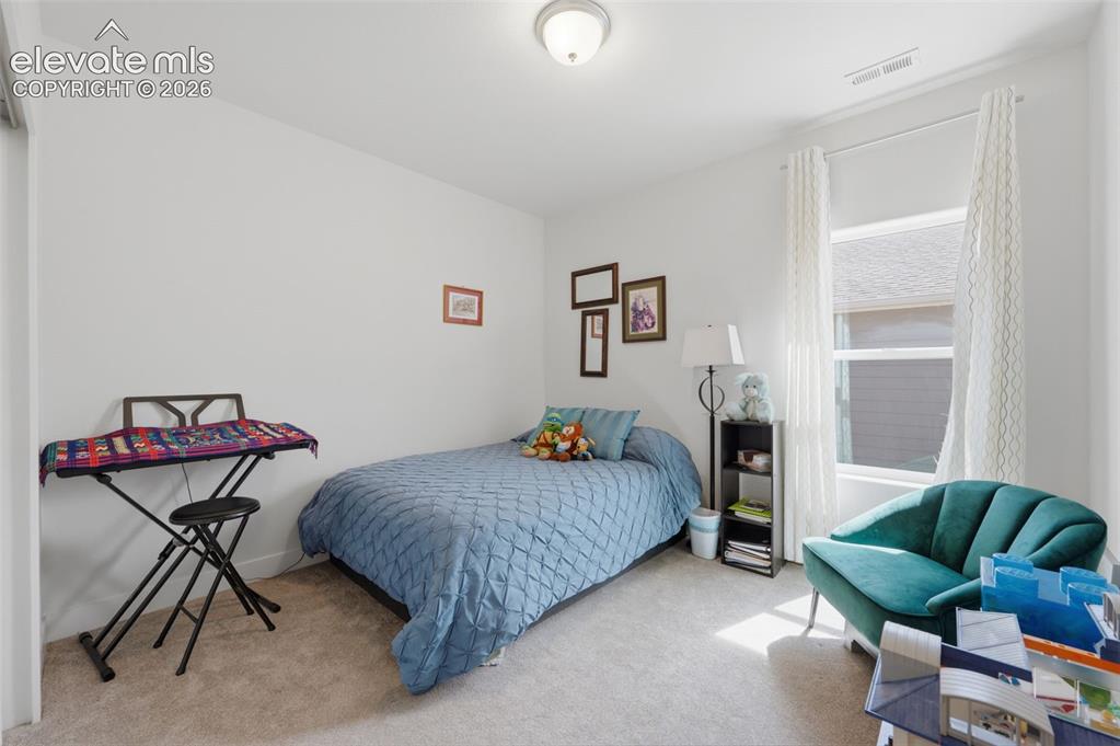 Image 15 of 25: Carpeted room featuring a single window with white curtains, a flush-mount
