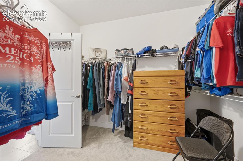 Image 16 of 25: Carpeted closet space featuring a white paneled door, built-in wire shelvin