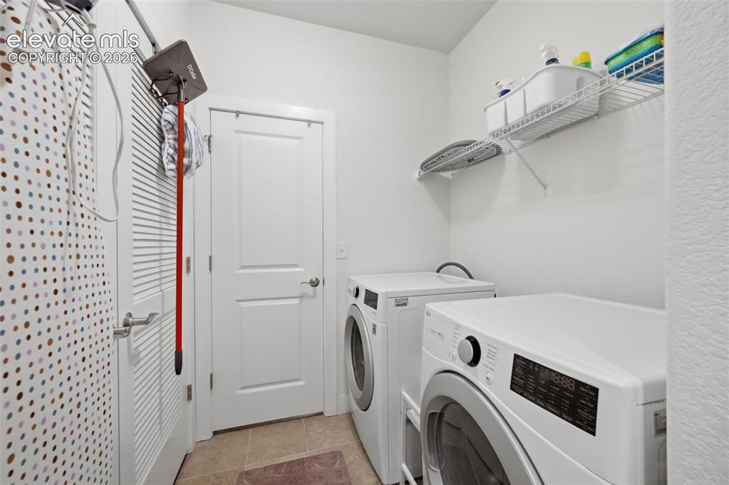 Image 17 of 25: Dedicated laundry area featuring a front-loading washer and dryer, tile flo
