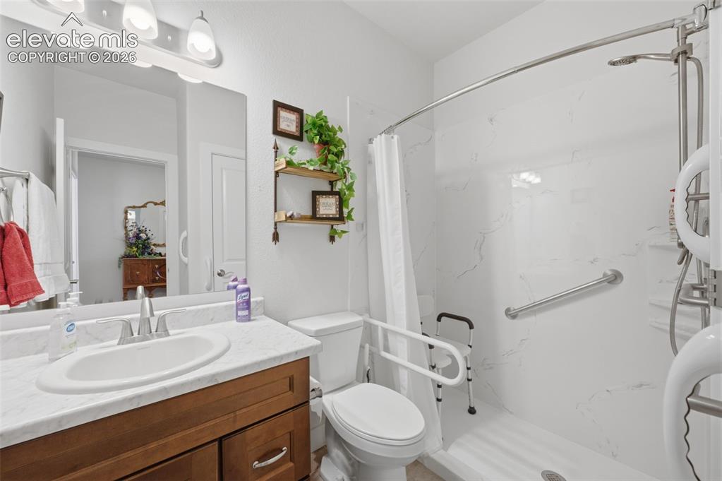 Image 18 of 25: Bathroom featuring a walk-in shower with white marbled wall panels and grab