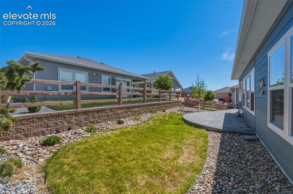 Image 20 of 25: Landscaped side yard featuring a retaining wall, wood fence, and a curved p