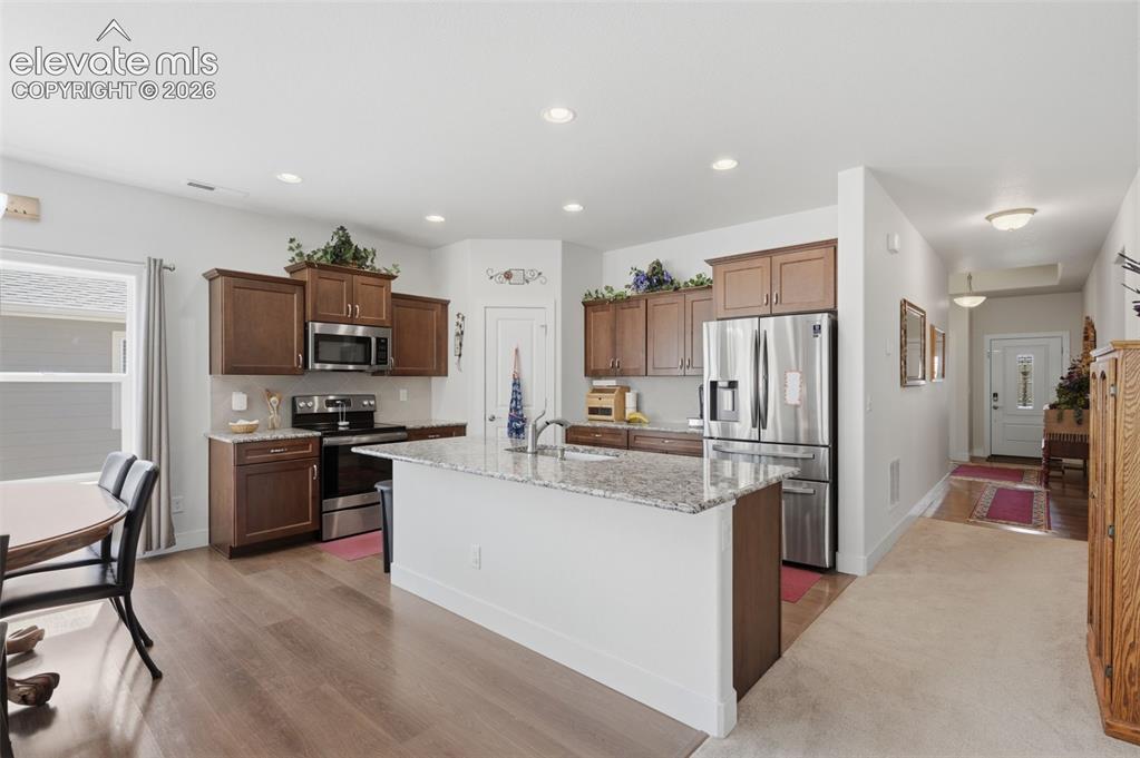 Image 3 of 25: Open-concept kitchen featuring wood-finish flooring, recessed lighting, and
